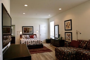 Un dormitorio con cama, cómoda, escritorio y sofá.