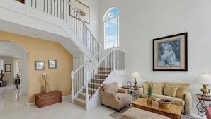 A spacious living area with a staircase, a sofa set, a coffee table, and a framed picture on the wall.