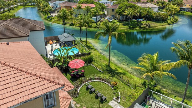 A residential area with a swimming pool, palm trees, and houses.