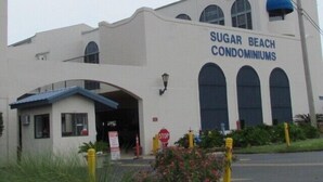 A building labeled "Sugar Beach Condominiums" with a covered entrance and multiple windows.