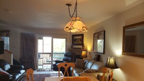 A living room with a dining table, chairs, a sofa, and a chandelier. There is a sliding glass door leading to an outdoor area. - Luxury Mountain Home  Mountain Views Free Wifi (Silverthorne)