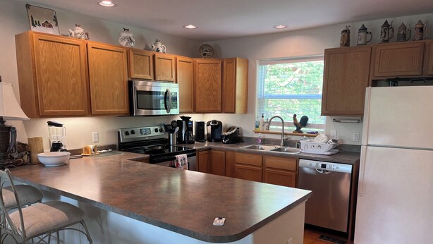A kitchen with wooden cabinets, a stainless steel refrigerator, a built-in oven, and a large island with bar stools. - Luxury Mountain Home  Mountain Views Free Wifi (Silverthorne)