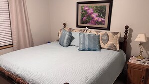 A neatly made bed with a quilted cover, a wooden headboard, and two pillows with leaf patterns. A framed picture of flowers hangs on the wall above the bed. - Luxury Mountain Home  Mountain Views Free Wifi (Silverthorne)
