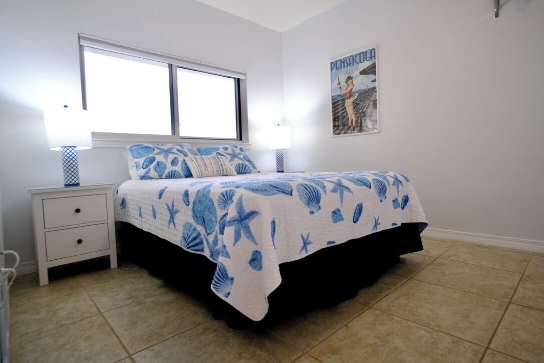 Ein Schlafzimmer mit Bett, Nachttisch, Fenster und einem Poster an der Wand.
