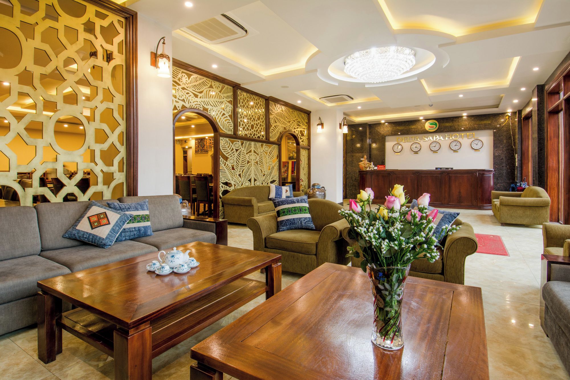 A hotel lobby with a reception desk, seating area, and decorative wall panels.