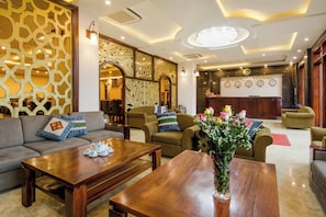 Un vestíbulo de hotel con mostrador de recepción, zona de estar y paneles decorativos en la pared.