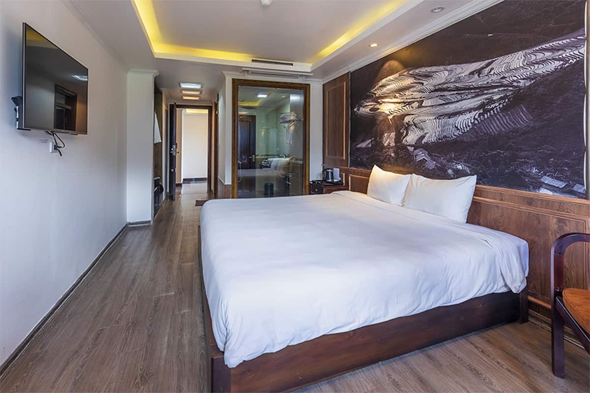 Habitación de hotel con una cama grande, un televisor de pantalla plana montado en la pared y un mural de gran tamaño.