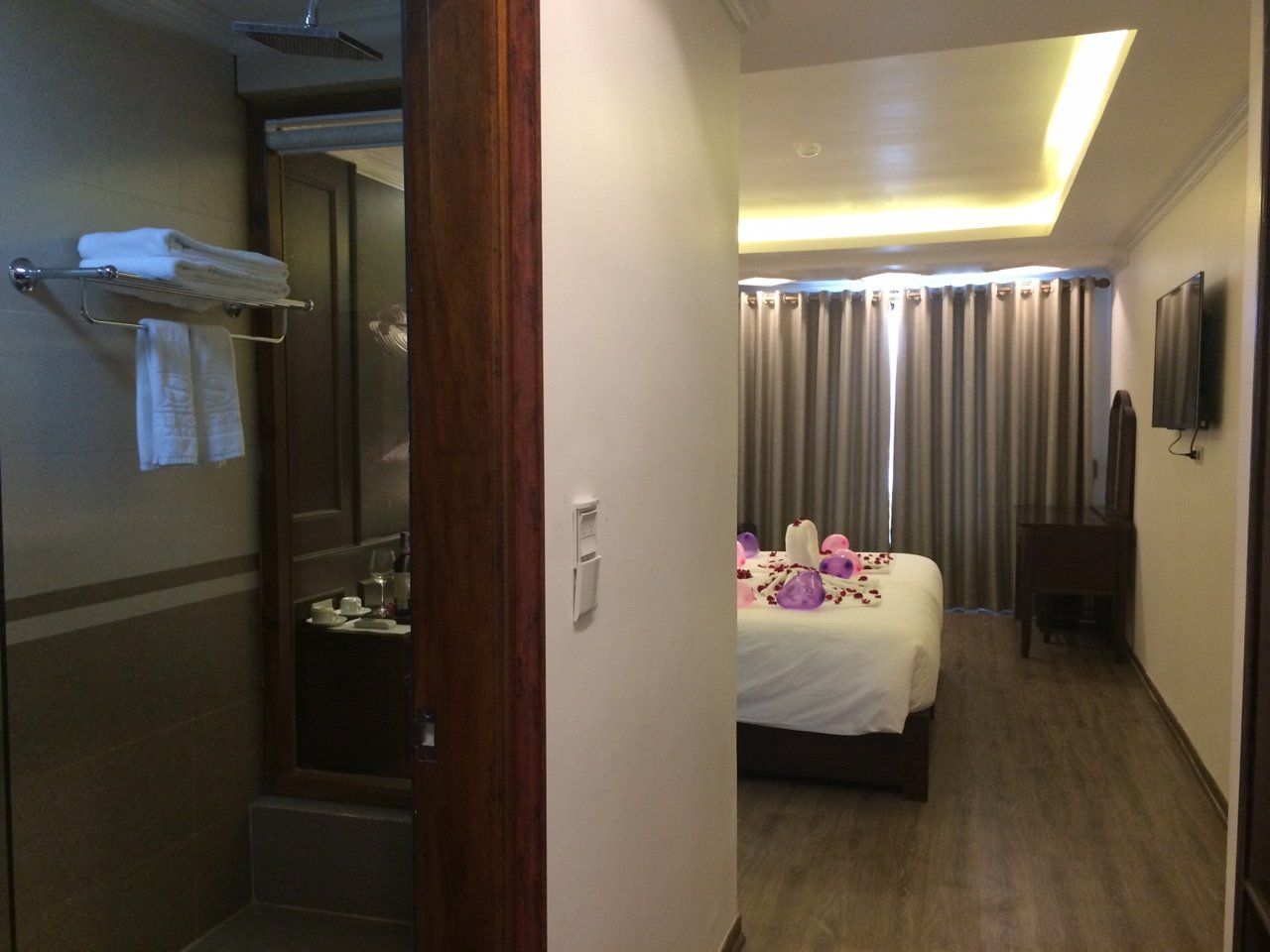 A hotel room with a bed, a bathroom with a shower, and a TV.