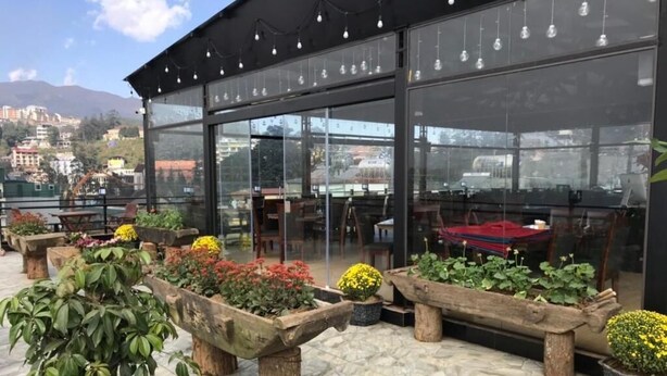 An outdoor seating area with wooden tables and benches, surrounded by potted plants and flowers. - Sapa Delta Hotel (Sa Pa)
