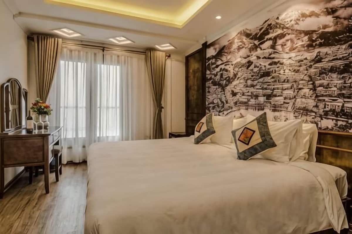 Un dormitorio con una cama grande, un escritorio con espejo y un tapiz en la pared.