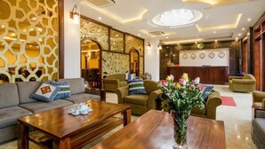 A hotel lobby with a reception desk, sofas, and a coffee table. - Sapa Delta Hotel (Sa Pa)