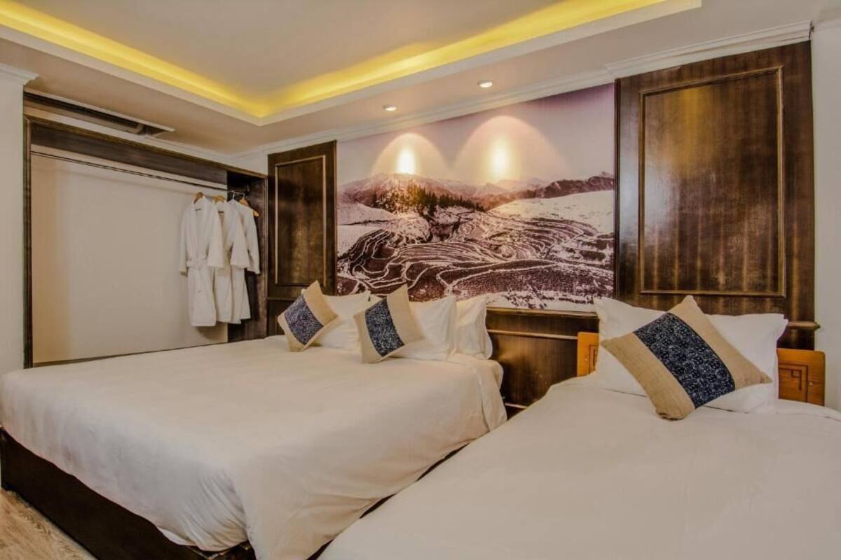 Habitación de hotel con dos camas, un mural grande en la pared y un perchero para abrigos.