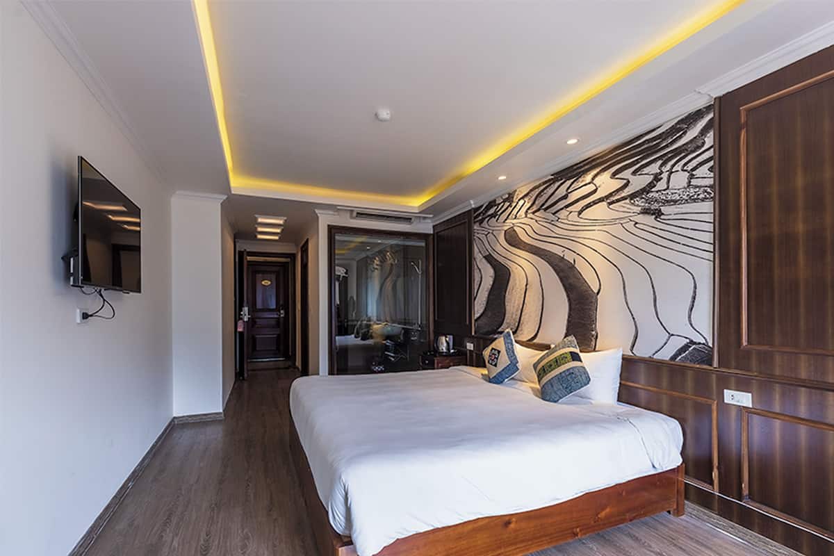 Una habitación de hotel moderna con una cama grande, un televisor de pantalla plana y un mural único en la pared.