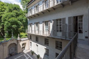 A multi-story building with balconies, a stone archway, and a courtyard with potted plants. - Palazzo del Carretto (Turin)