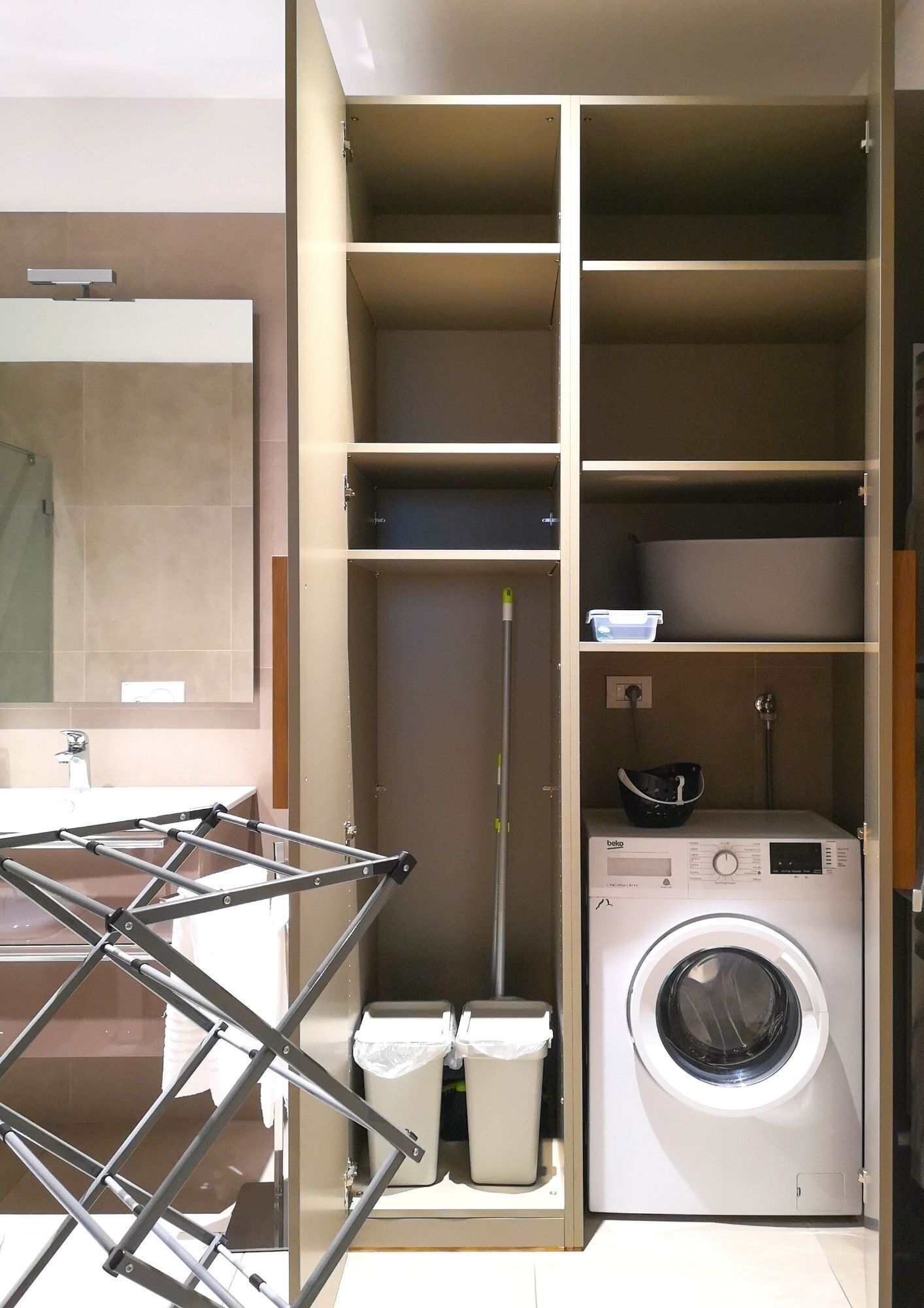 A laundry area with a washing machine, a drying rack, and a mop.