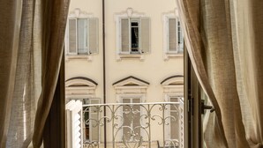 A view through a window with curtains, revealing a building with balconies and a metal gate. - Palazzo del Carretto (Turin)