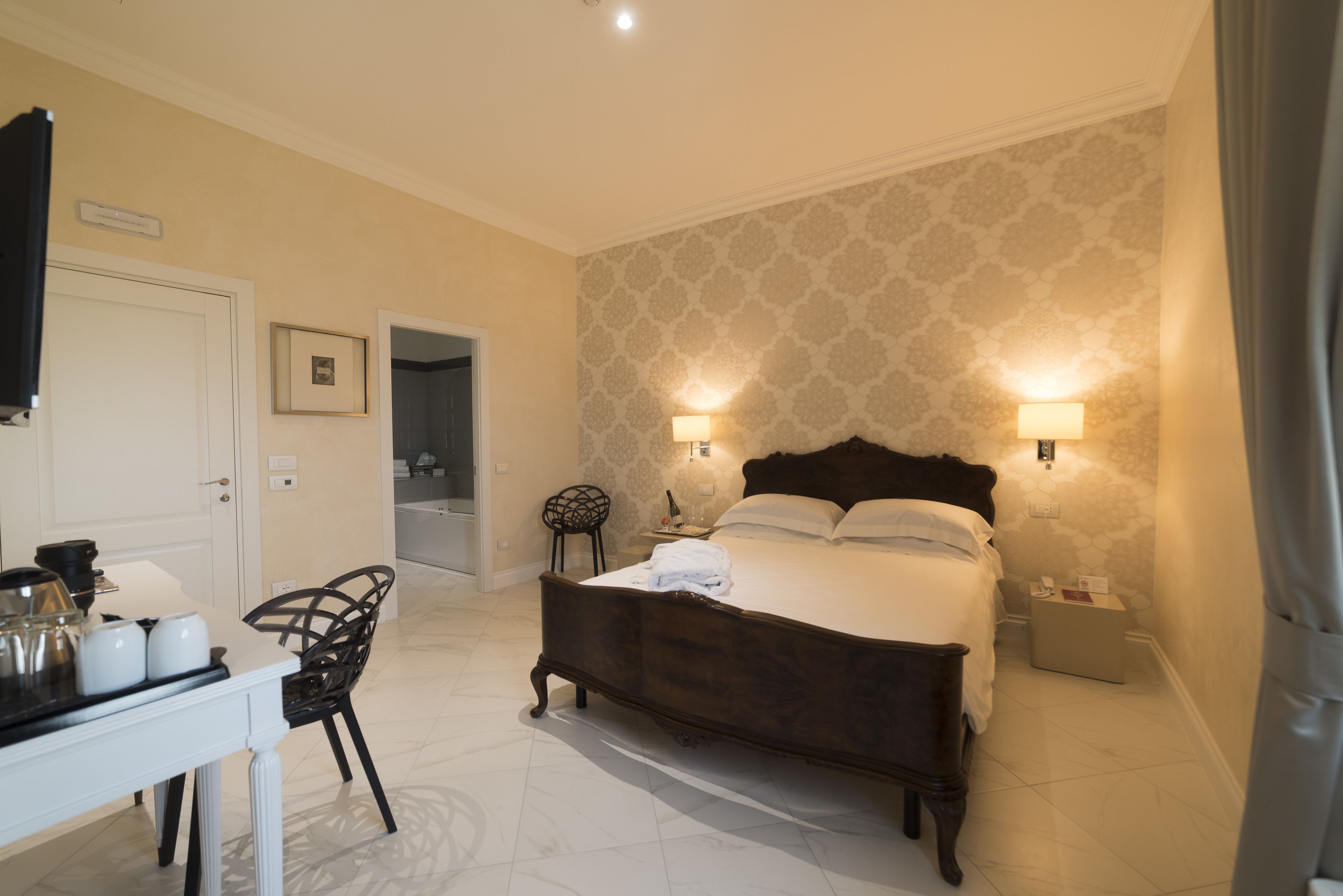 Une chambre à coucher avec un grand lit, des lampes de chevet, un bureau avec une chaise et une petite table.