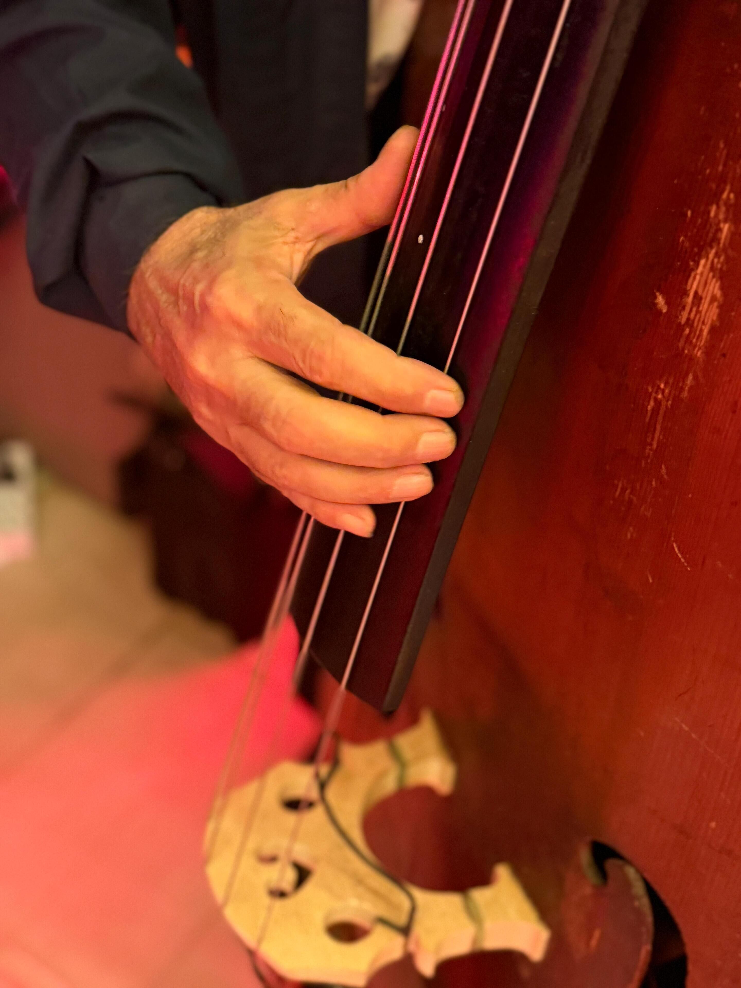 Eine Hand hält ein Cello in Nahaufnahme.