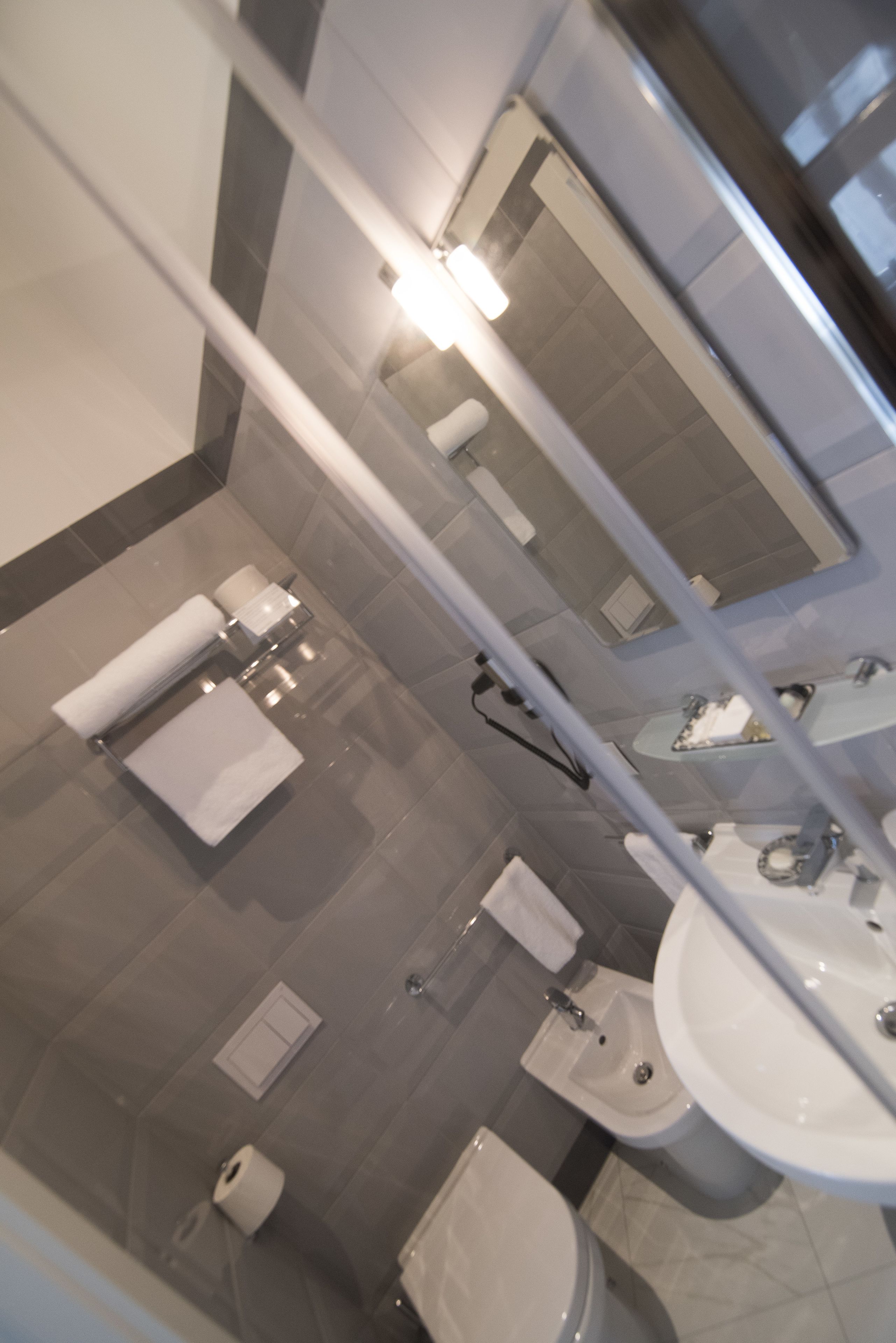 Un baño moderno con inodoro, bidé, lavabo y espejo.