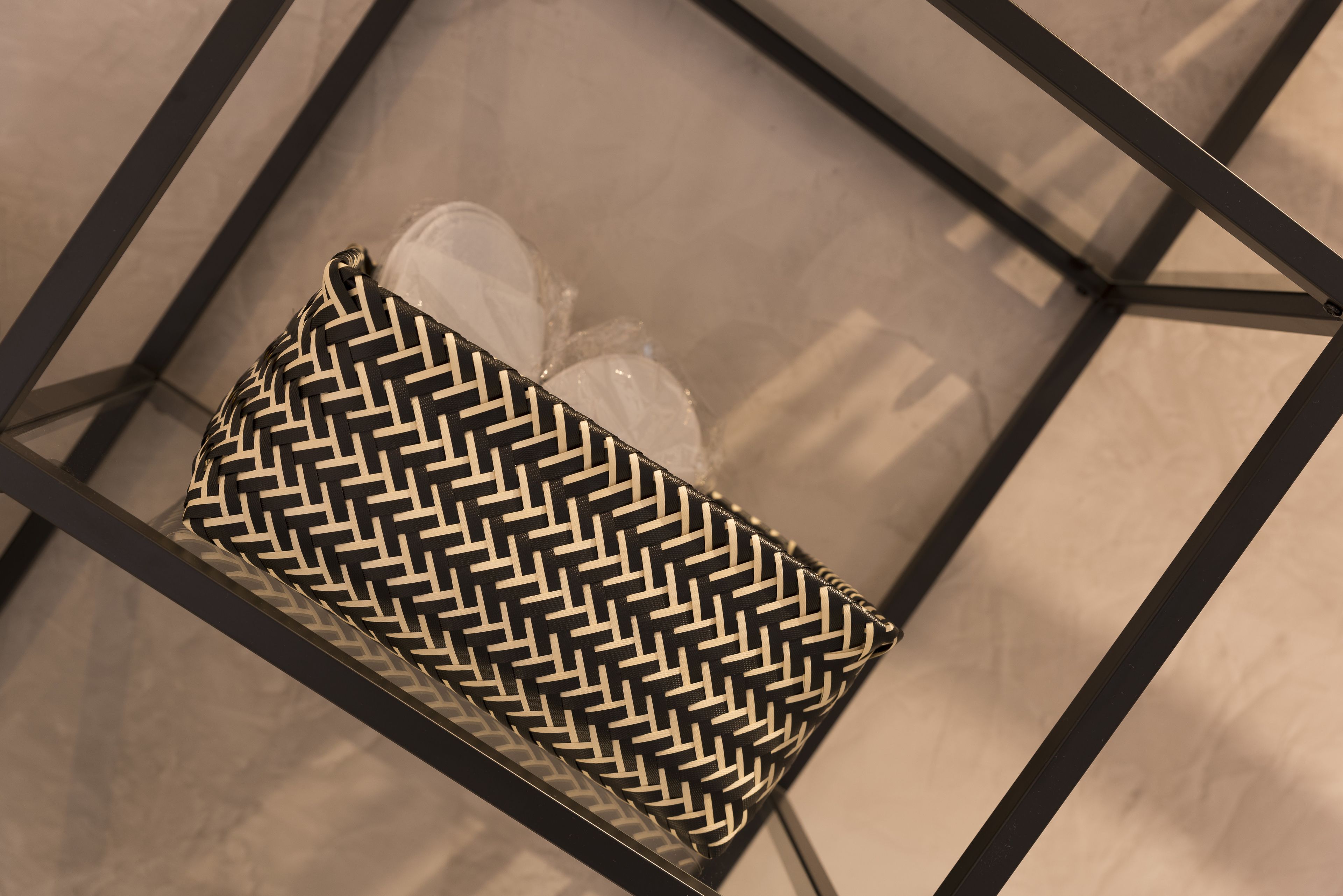 A geometric-patterned bag placed on a glass table with metal frames.
