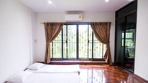 Quarto de hotel com duas camas, uma janela grande com grades de ferro decorativas e uma porta de vidro deslizante que dá para uma varanda.