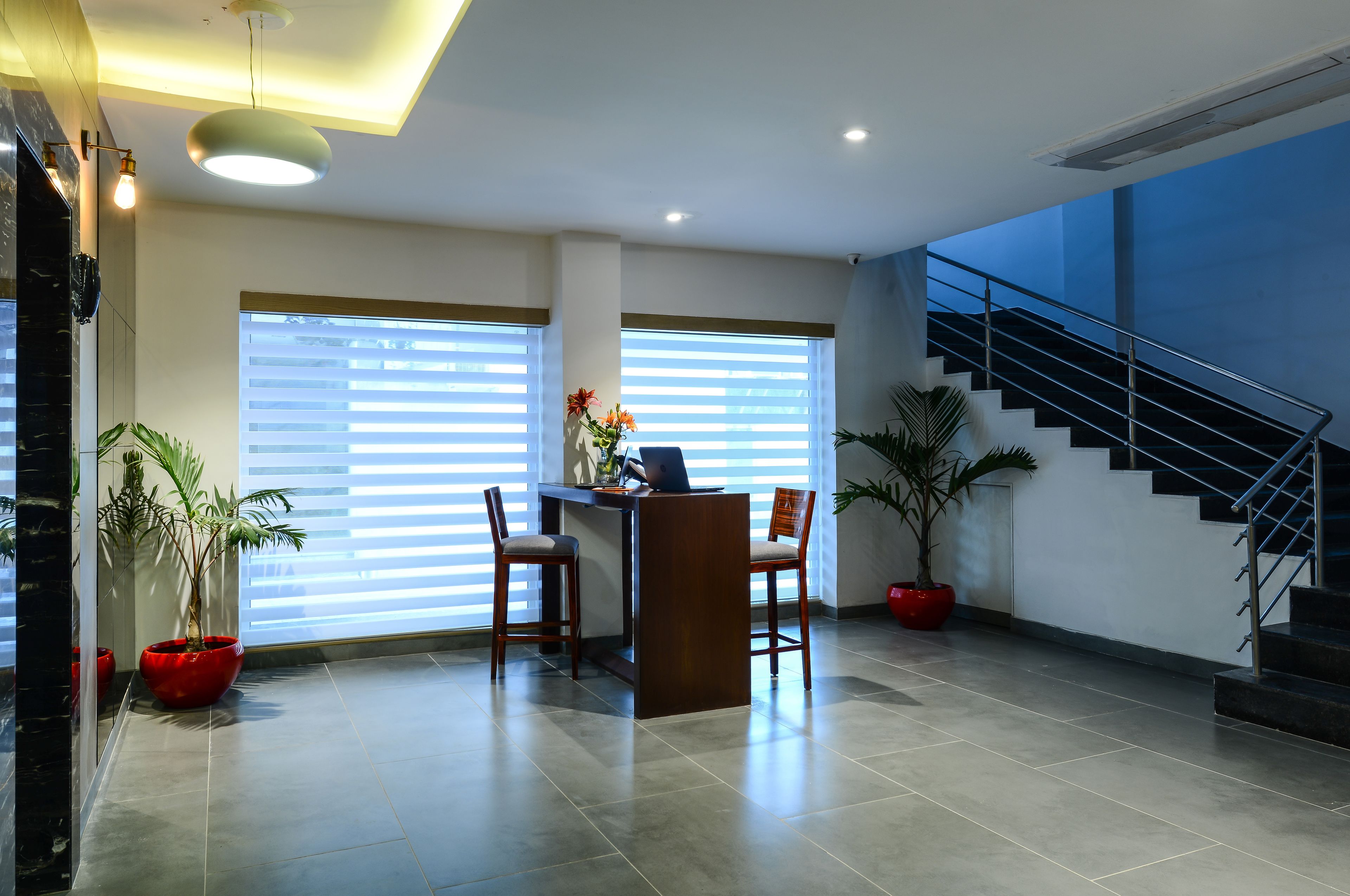 A modern office space with a desk, chairs, and potted plants.