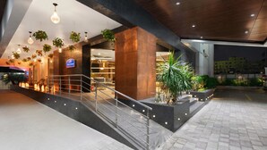 A modern hotel lobby with a staircase, potted plants, and a reception desk.