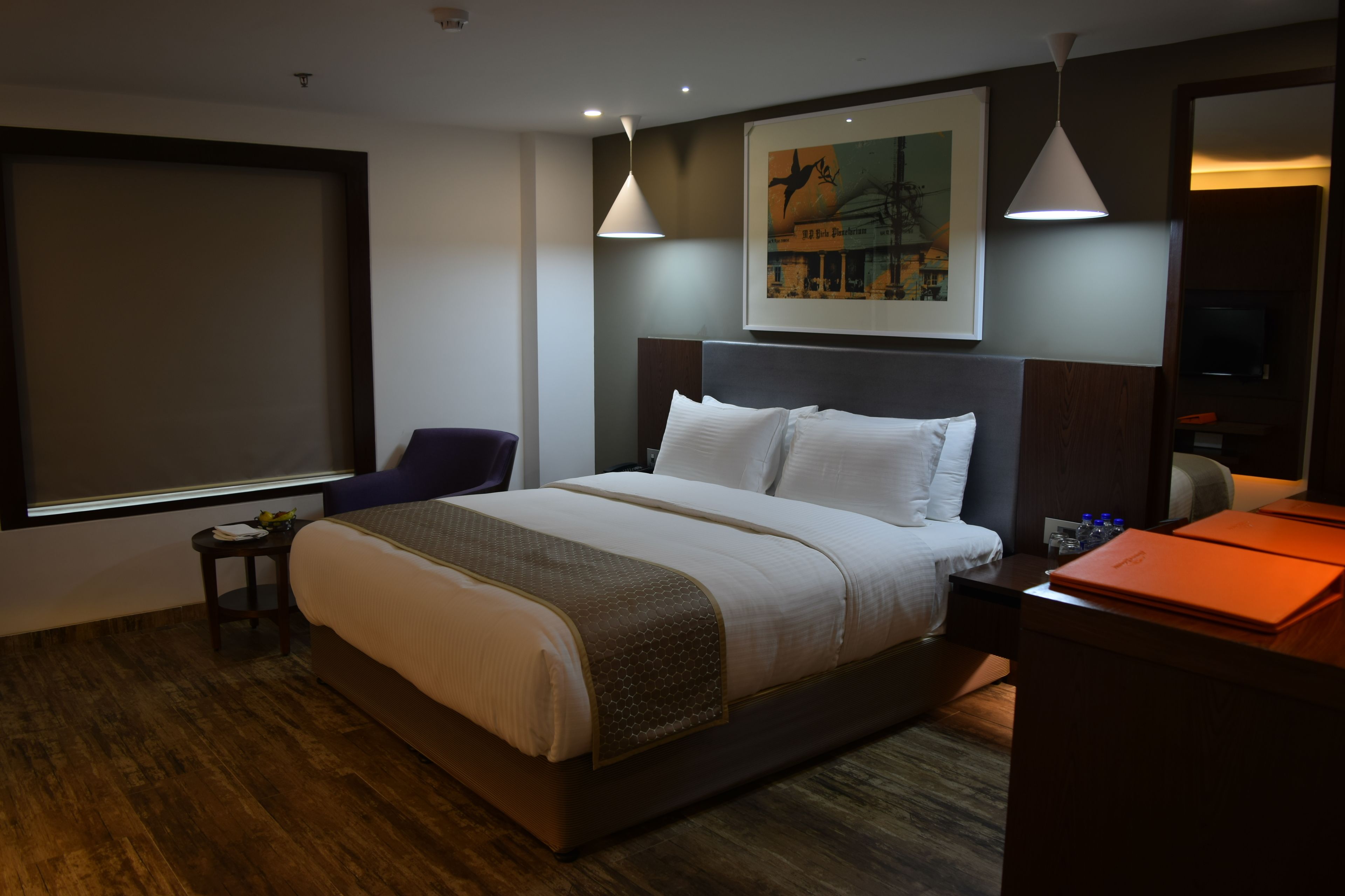 A hotel room with a large bed, a desk, a chair, and a TV.