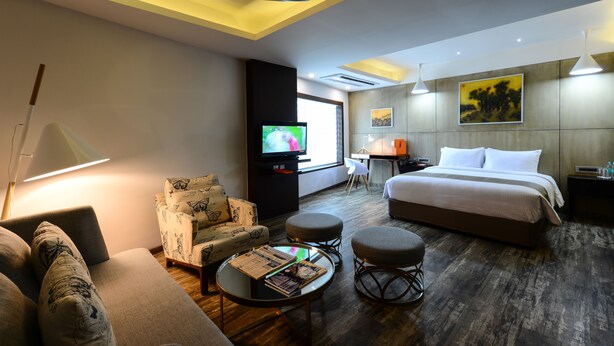 A hotel room with a bed, a sofa, a TV, a desk, and a chair.