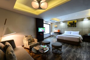 Een hotelkamer met een bed, een bank, een televisie, een bureau en een stoel.