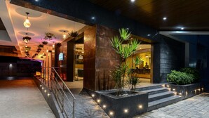 A modern building entrance with a staircase, potted plants, and hanging lights.