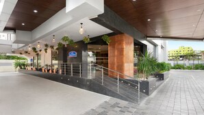A modern hotel entrance with a spacious lobby, a staircase, and a sign indicating a restaurant.