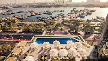 Relax by the rooftop pool surrounded by sun loungers and umbrellas, with stunning views of the marina and city skyline.