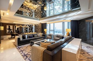 Un salon moderne avec un canapé d’angle, une table basse et un plafond haut orné d’un luminaire original.