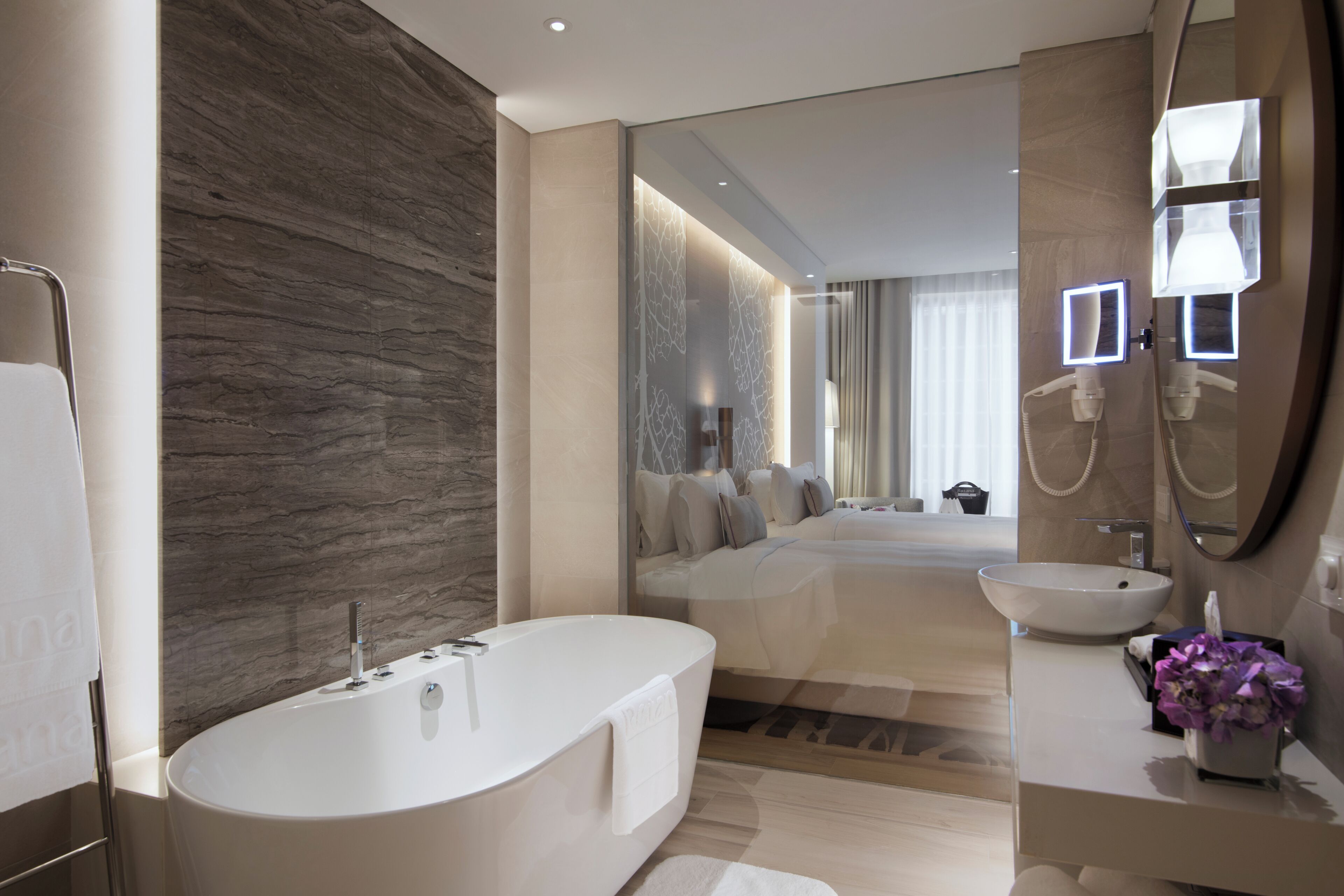 Ein modernes Badezimmer mit einer freistehenden Badewanne, einem Waschtisch mit Spiegel und einem großen Spiegel über dem Waschbecken.
