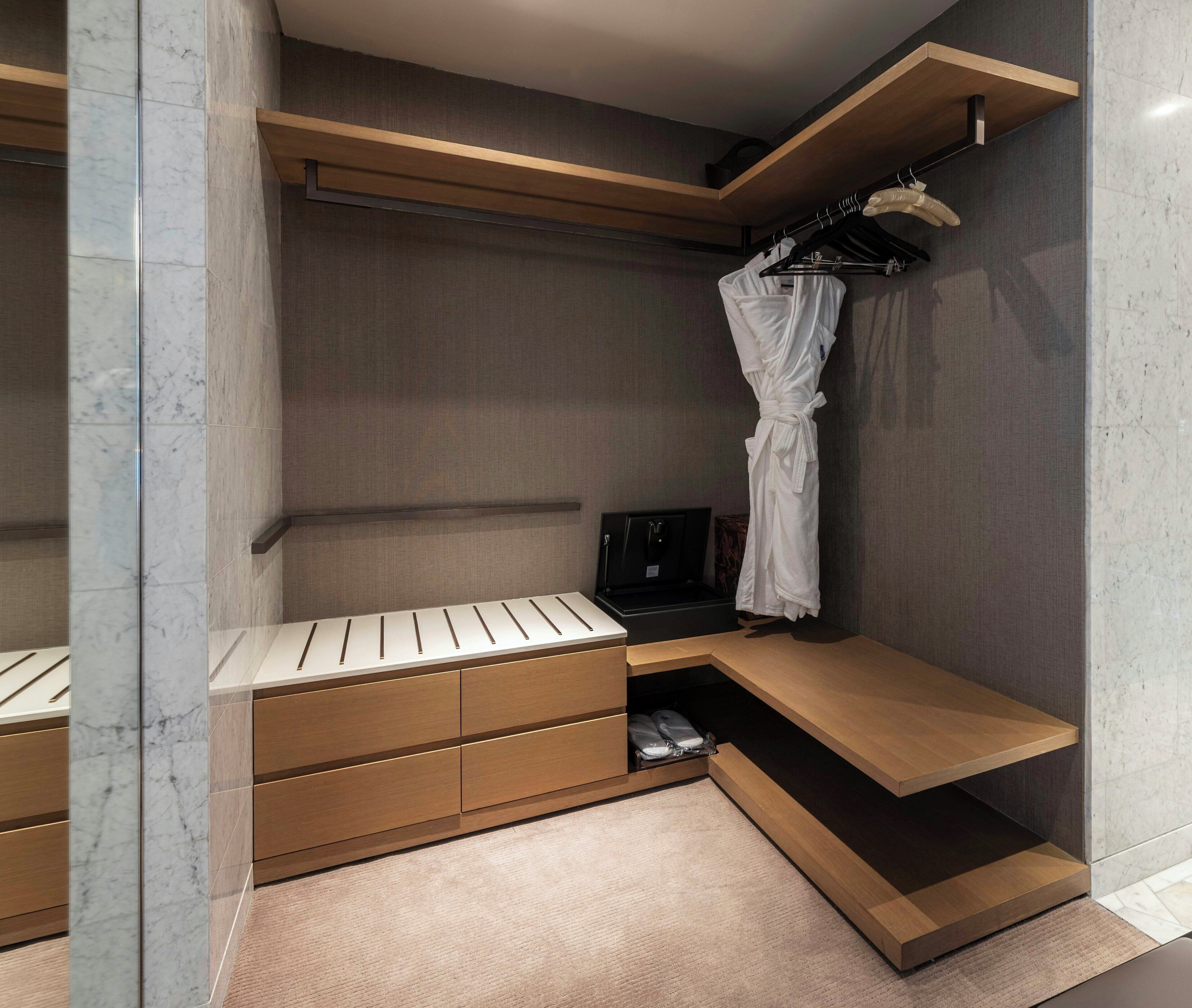 A modern bathroom with a wooden vanity, a robe hanging on a rack, and a towel rack.