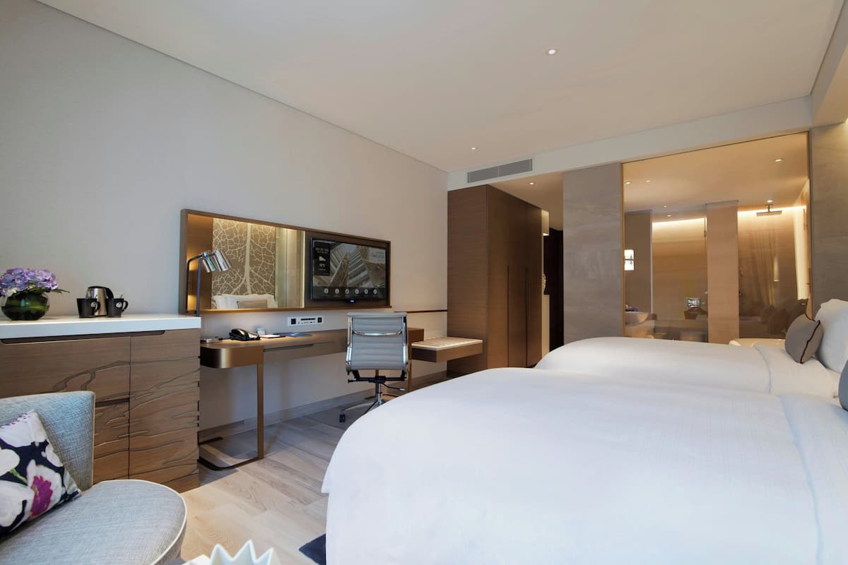 Una habitación de hotel moderna con cama, escritorio, silla y un espejo grande.
