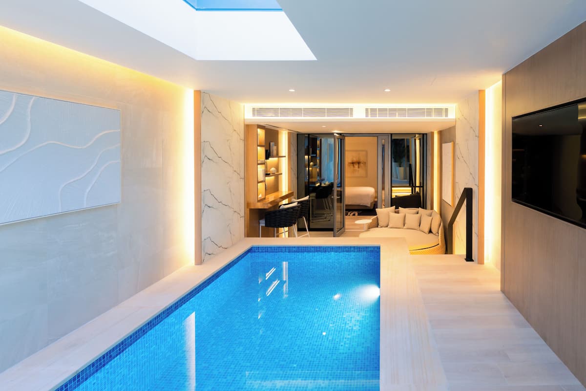 Un interior moderno con piscina, comedor y sala de estar con sofá y televisor.