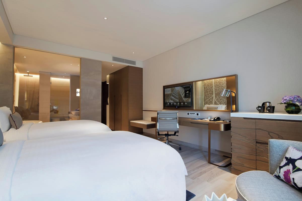 Una habitación de hotel moderna con una cama grande, un escritorio con computadora, una silla y una pequeña zona de estar.