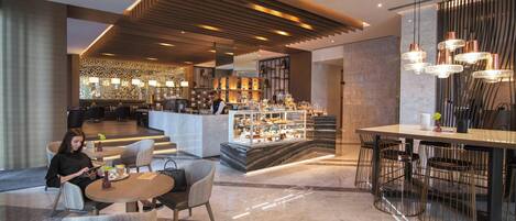 A modern hotel lobby with a bar area, seating arrangements, and a decorative ceiling.