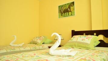 Habitación de hotel con dos camas, ropa de cama estampada con motivos florales, un cuadro de caballos y una almohada con forma de cisne.