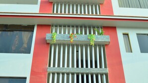 En bygning med en facade i rødt og hvidt, med en balkon med lodrette sprosser og blomsterkasser.