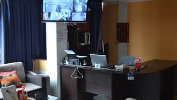 A hotel reception area with a desk, computer, and television displaying a video feed.