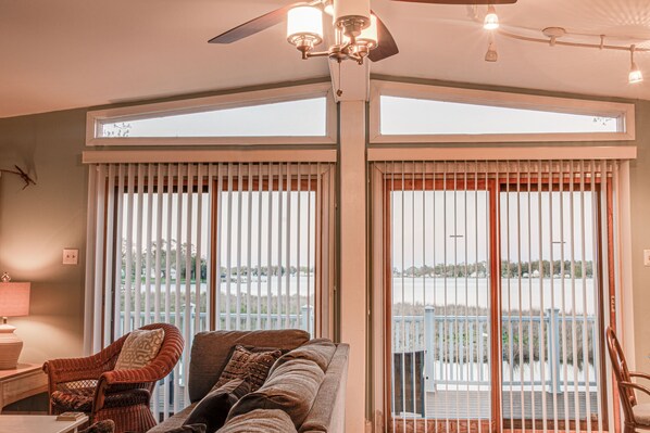 A room with a large window, a ceiling fan, and a view of a body of water.