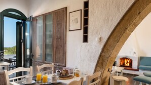 Comedor con una mesa preparada para el desayuno, chimenea y vistas al exterior.
