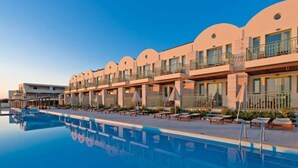 Un hotel con piscina, varios balcones y cielo despejado.