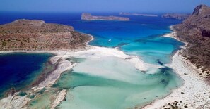 Eine Luftaufnahme einer Küstenregion mit Strand, klarem Wasser und felsigem Gelände.
