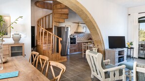 Amplia sala de estar con escalera de madera, una mesa de comedor y un televisor.