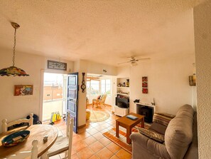 A living room with a sofa, a coffee table, a TV, and a fireplace. There is a balcony door leading outside.
