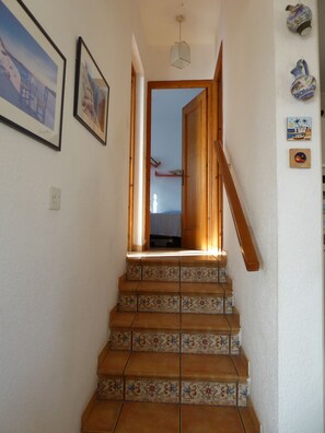 Una escalera con baldosas estampadas que lleva a una puerta abierta.